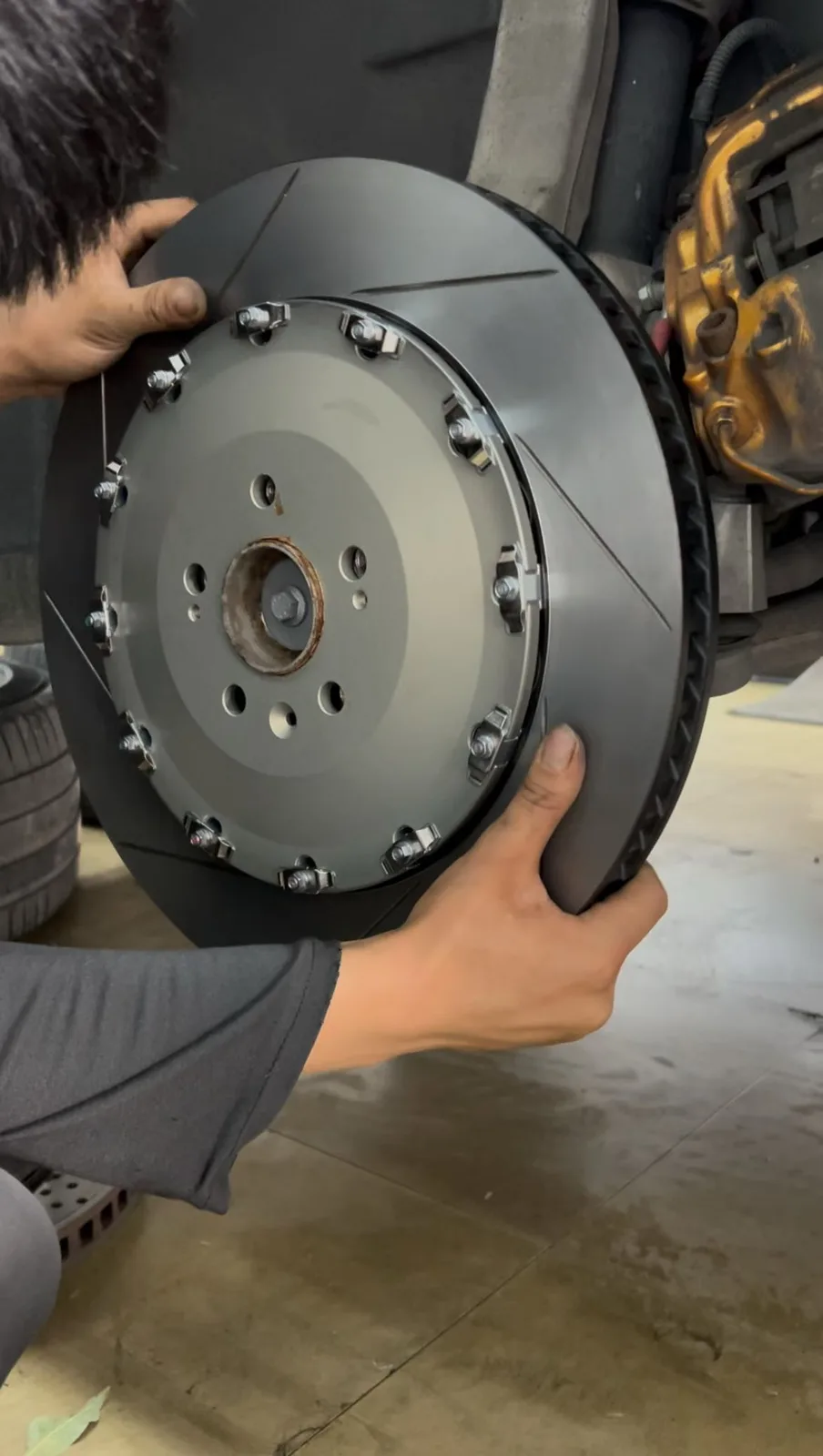Technician mounting 405mm two-piece brake rotor on Volvo XC90 hub